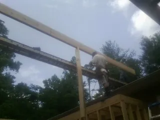 Carpenter setting a ridge beam over a new addition frame — Ice Dam Removal by Roofing Brothers in Gwynn