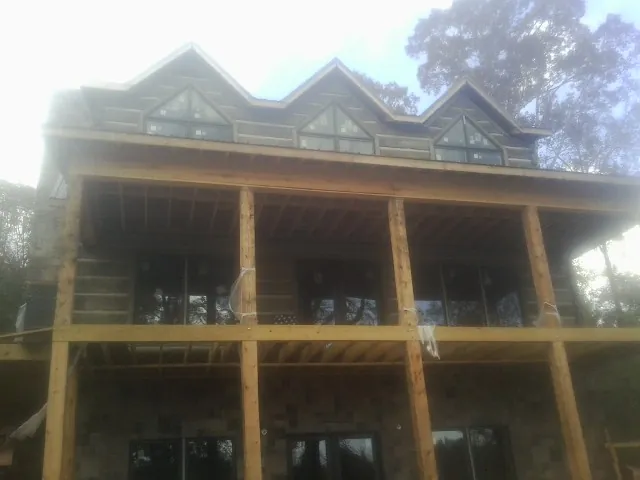 Dormers and porch framing on a large log home under construction — Roof Coating work by our crew in Gwynn