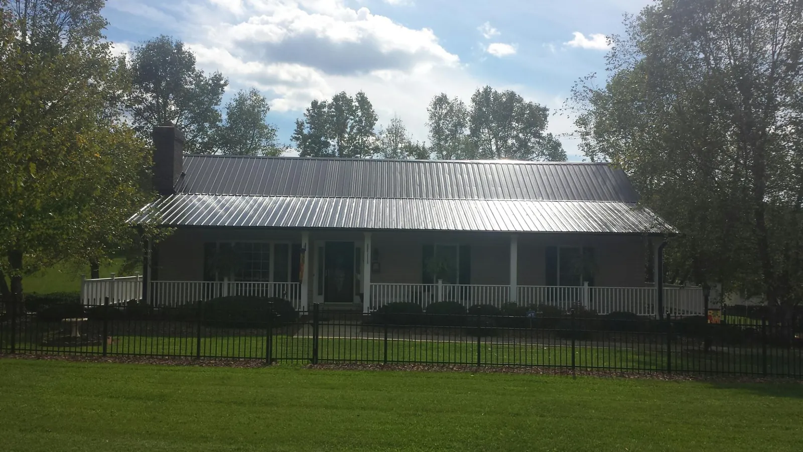 Gray metal roof on a brick ranch with a full width front porch — Gutter Guard Installation work by our crew in Gwynn