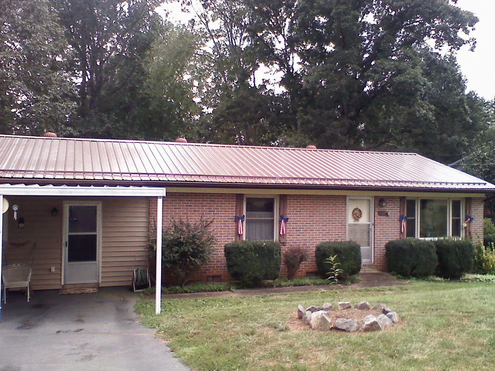 Bronze metal roof and carport on a brick ranch home — Roof Repair work by our crew in Gwynn