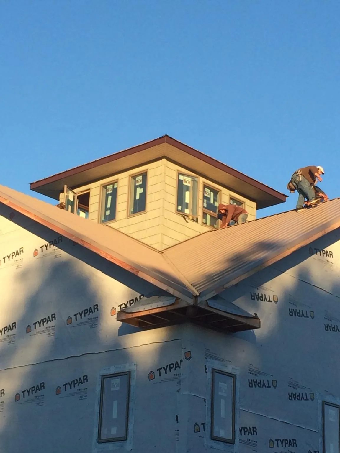 Roofers working around a rooftop cupola on a new metal roof at sunset — Roof Waterproofing in Gwynn by Roofing Brothers